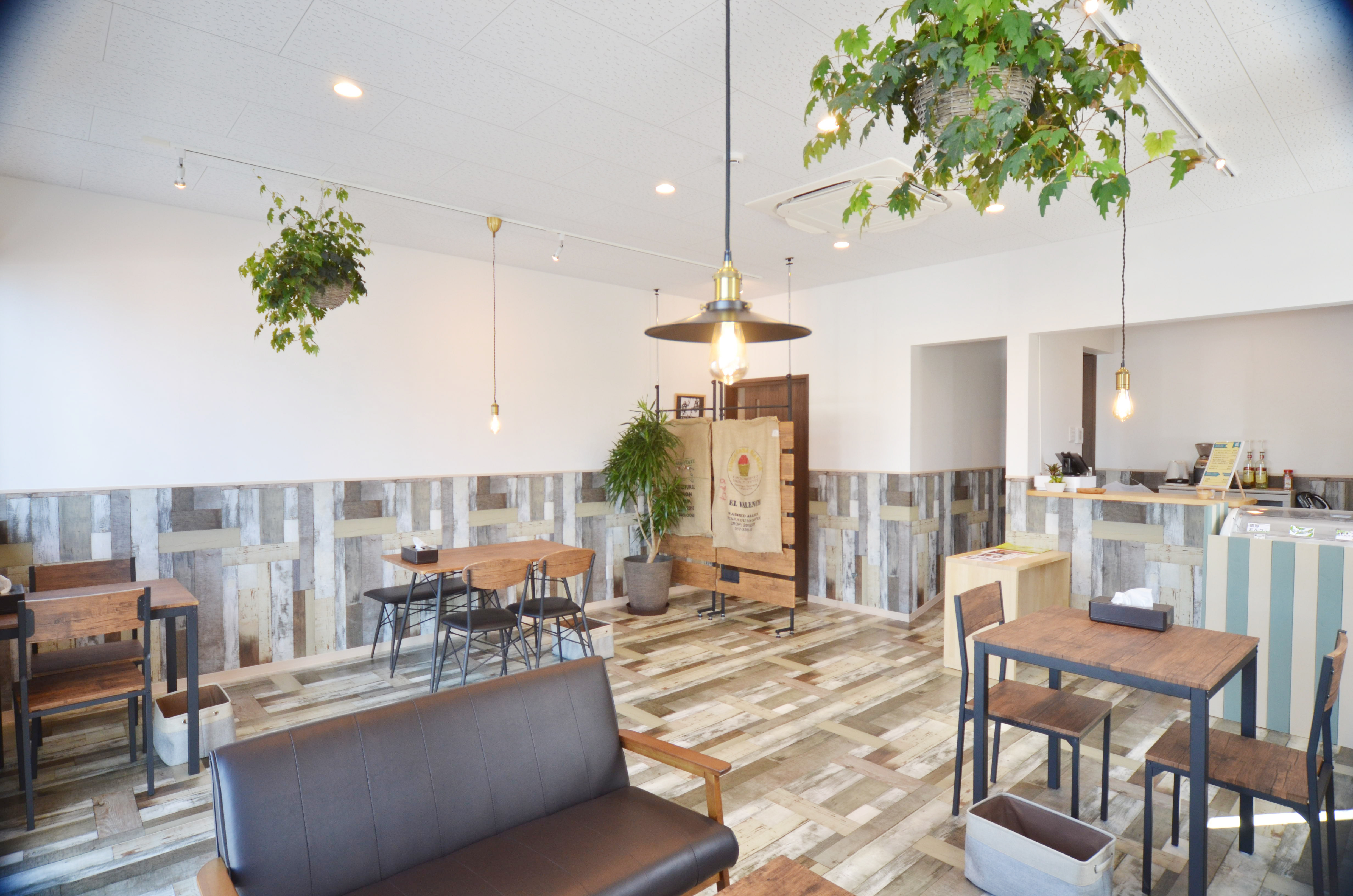 観葉植物と木のテーブル、ソファがあるYAMBARU COFFEEの店内